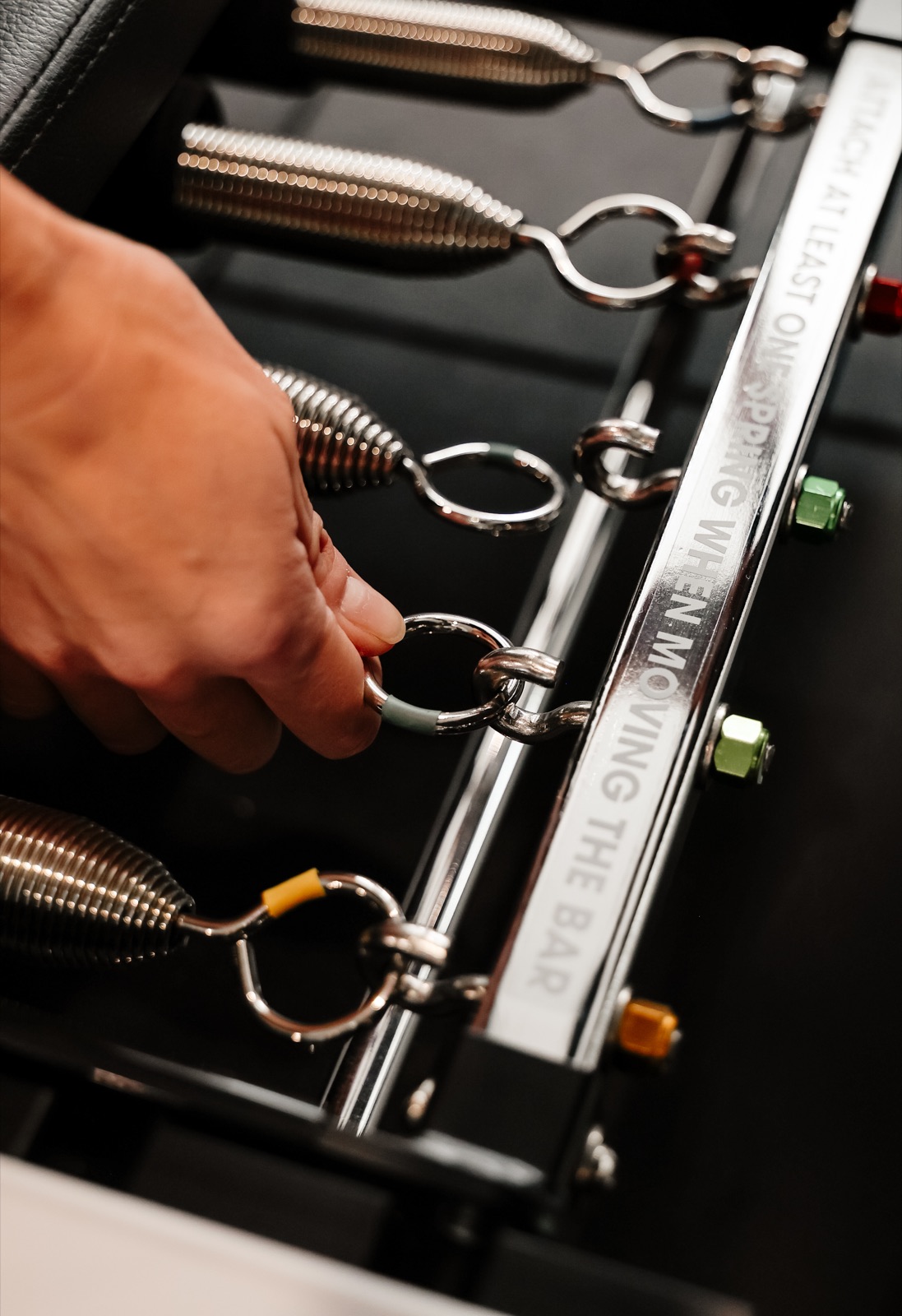 Close-up of a hand adjusting the springs on a reformer